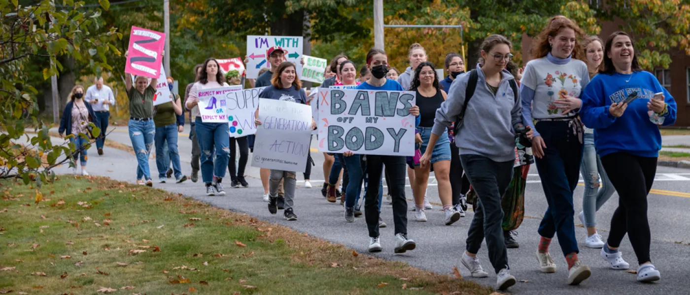 U N E students holding posters and walking during the Women's March