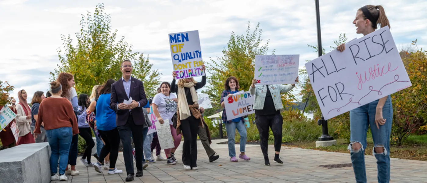 U N E students holding posters and walking during the Women's March