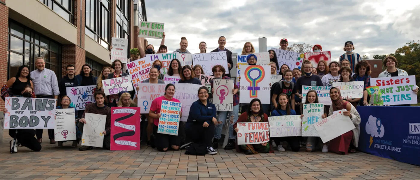 U N E students holding posters and walking during the Women's March