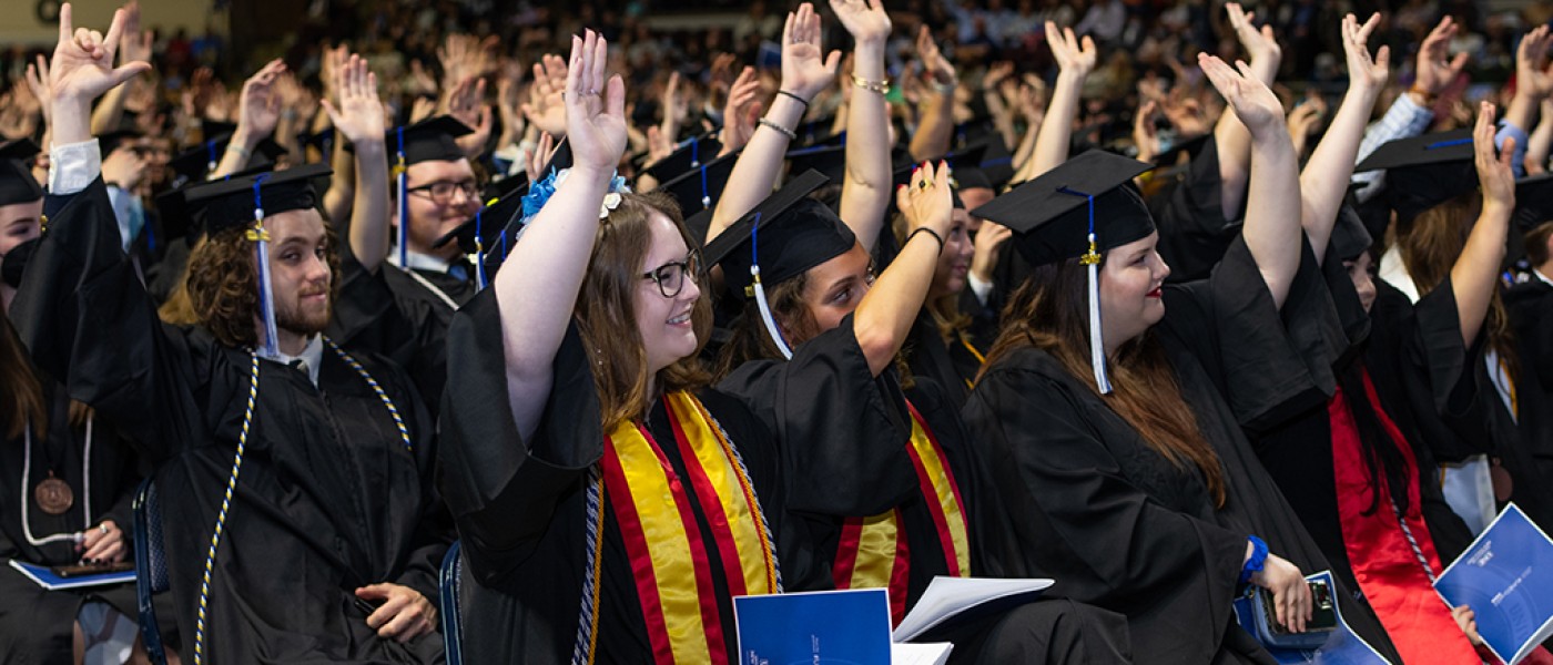 Students raise their hands when asked a question by the Commencement Speaker