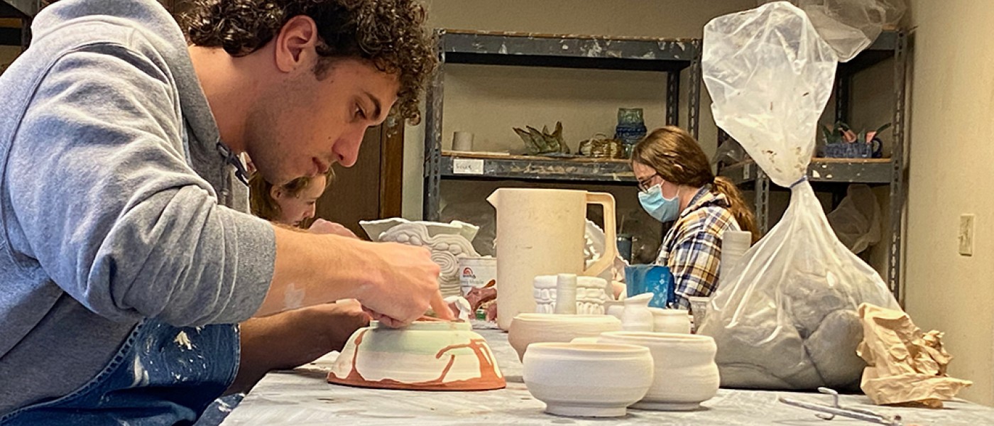 U N E student making pottery