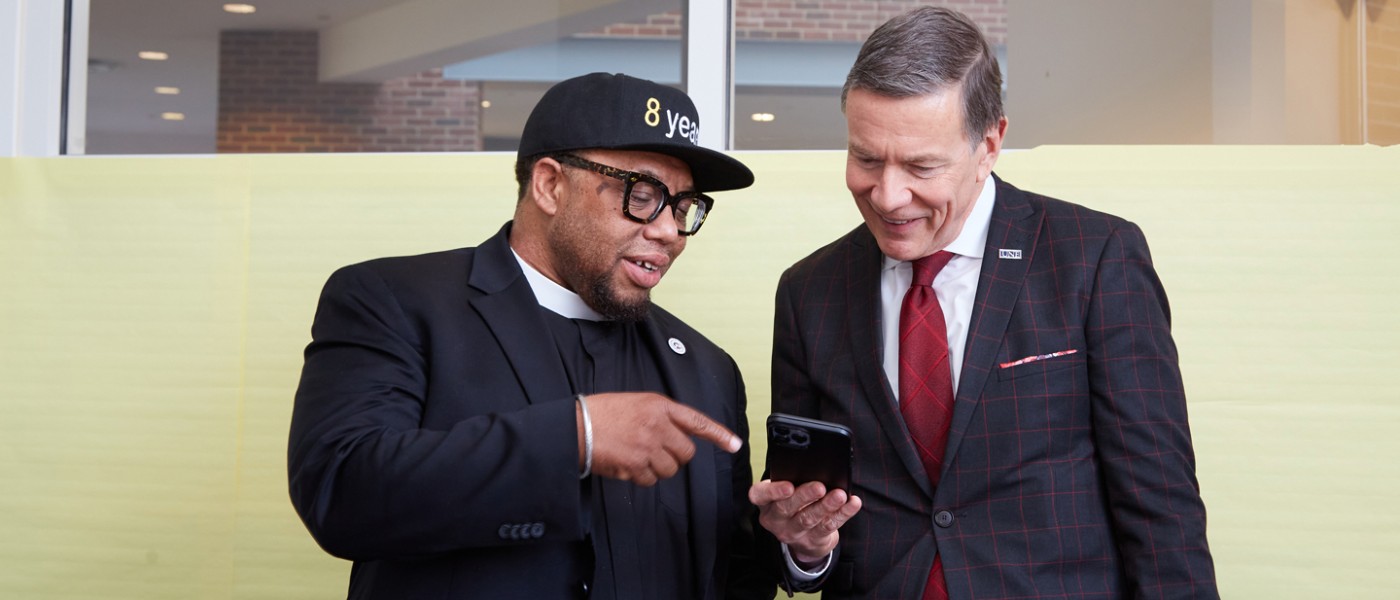 Reverend Lennox Yearwood and President Herbert looking at a cellphone screen 