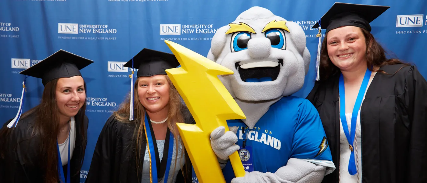 Three U N E students pose with University mascot Stormin' Norman