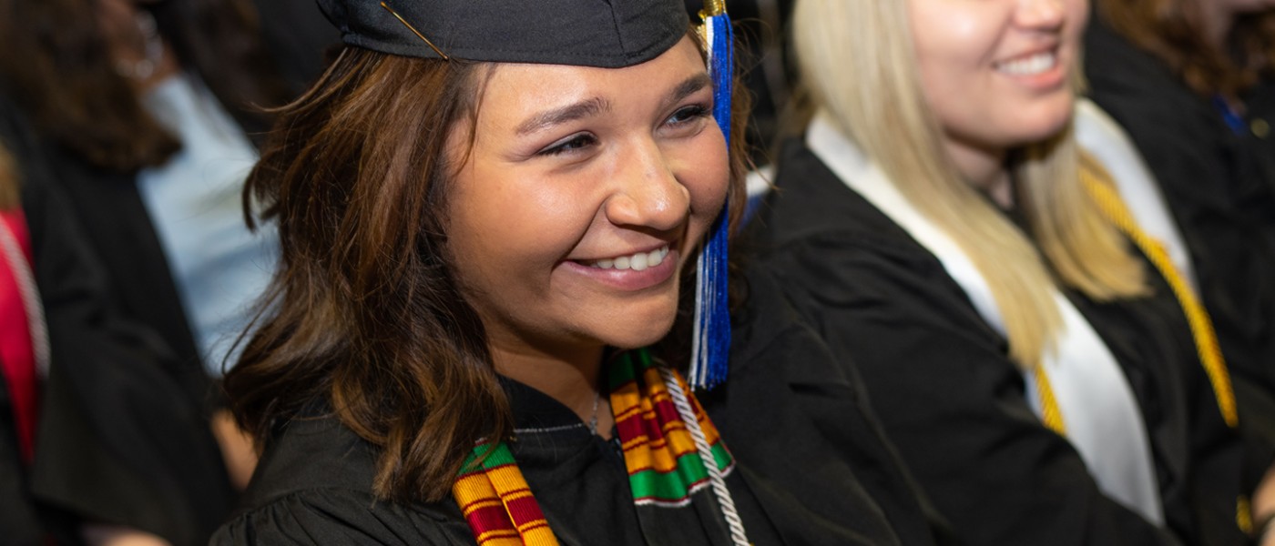 A graduating U N E student smiling during Commencement