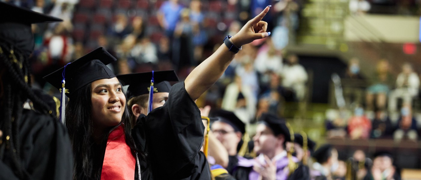 A graduating U N E student points their finger into the crowd