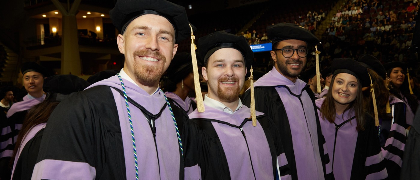 Four U N E graduating dental students smiling during Commencement
