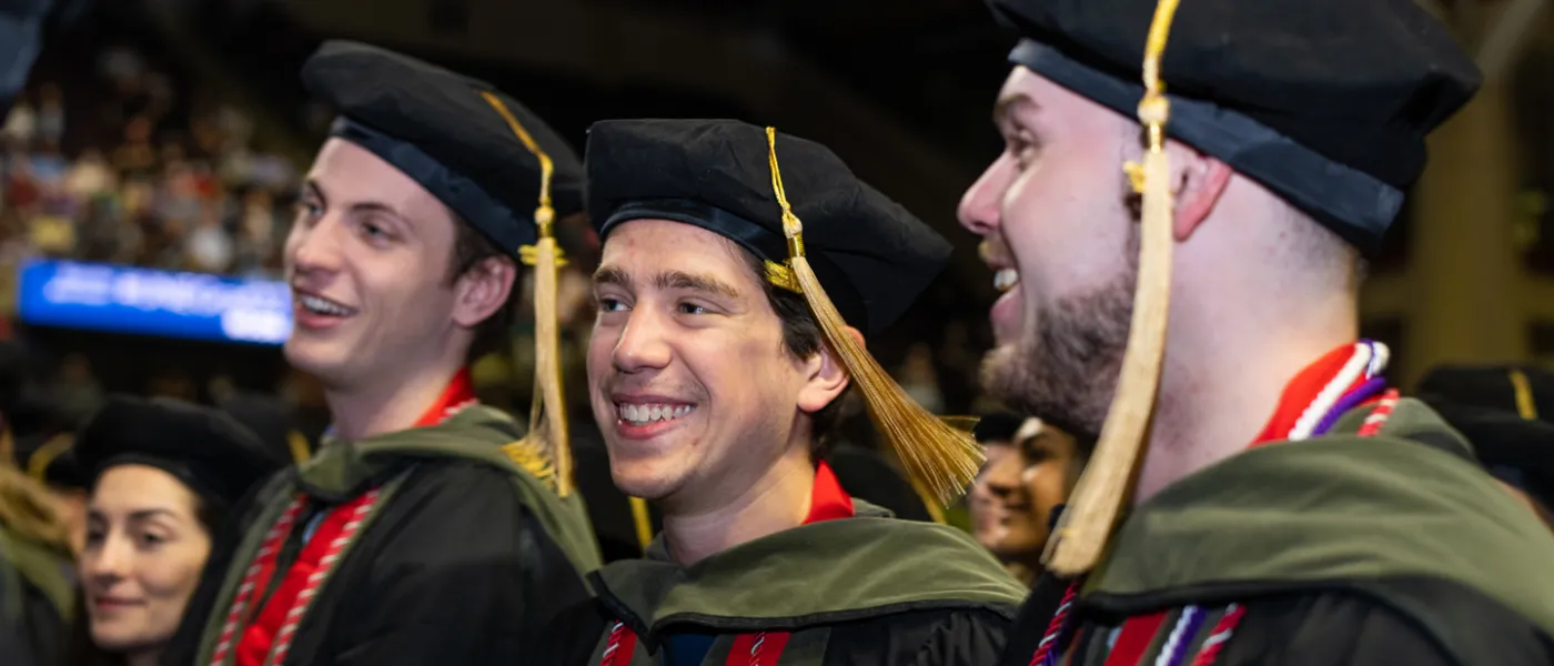 Three graduating U N E students smiling during Commencement