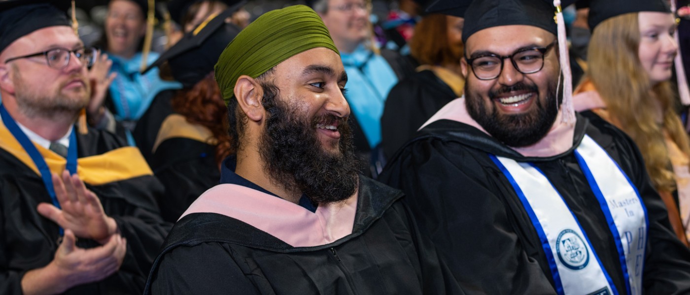 Two graduating U N E students smiling during Commencement