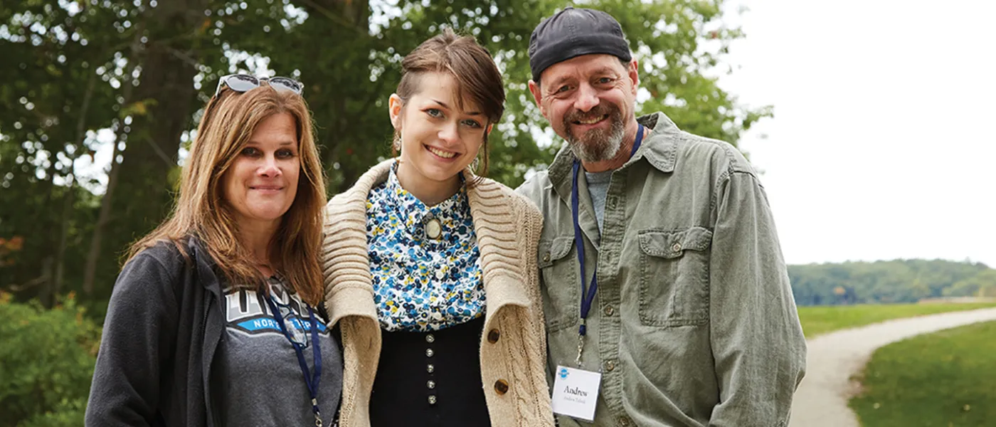 A U N E student stands with their parents