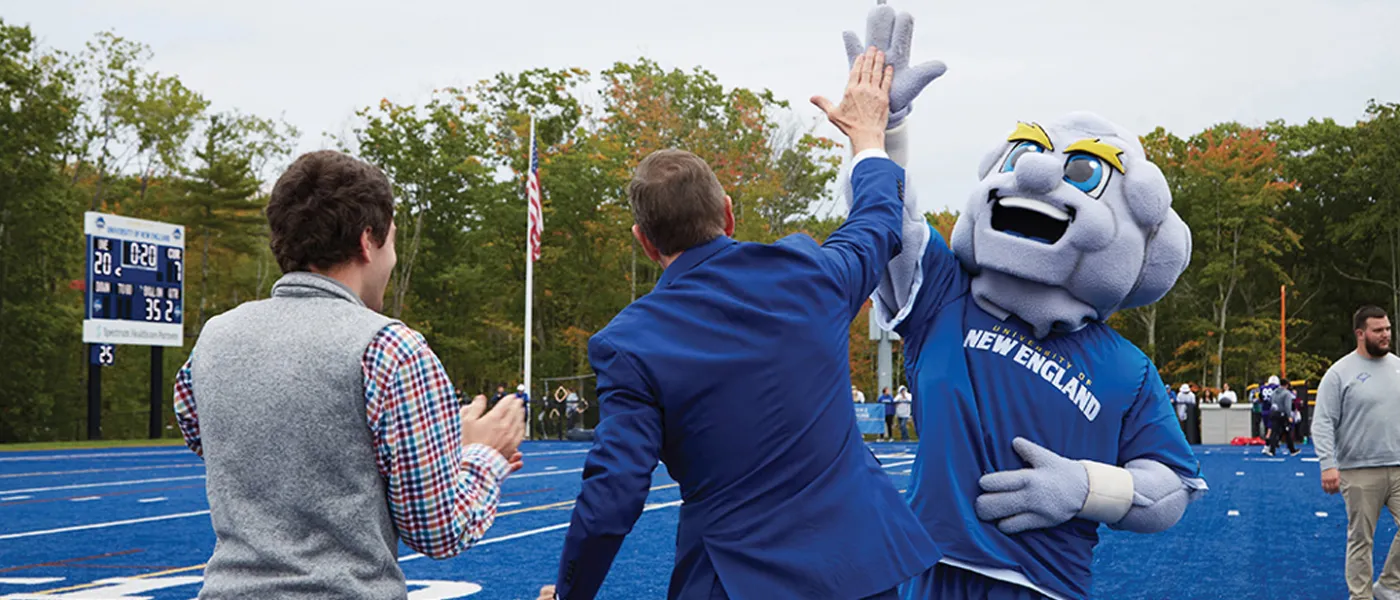 President Herbert high-fives Stormin' Norman on the U N E football field