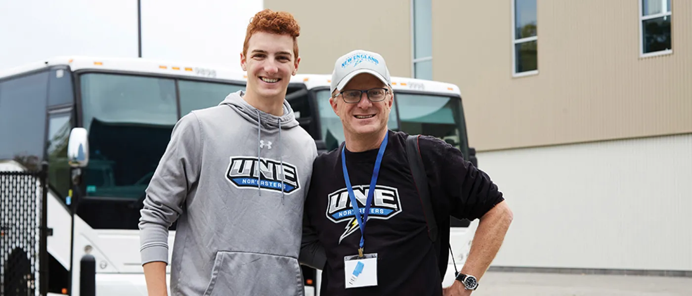 A U N E student stands with their father in U N E sweatshirts
