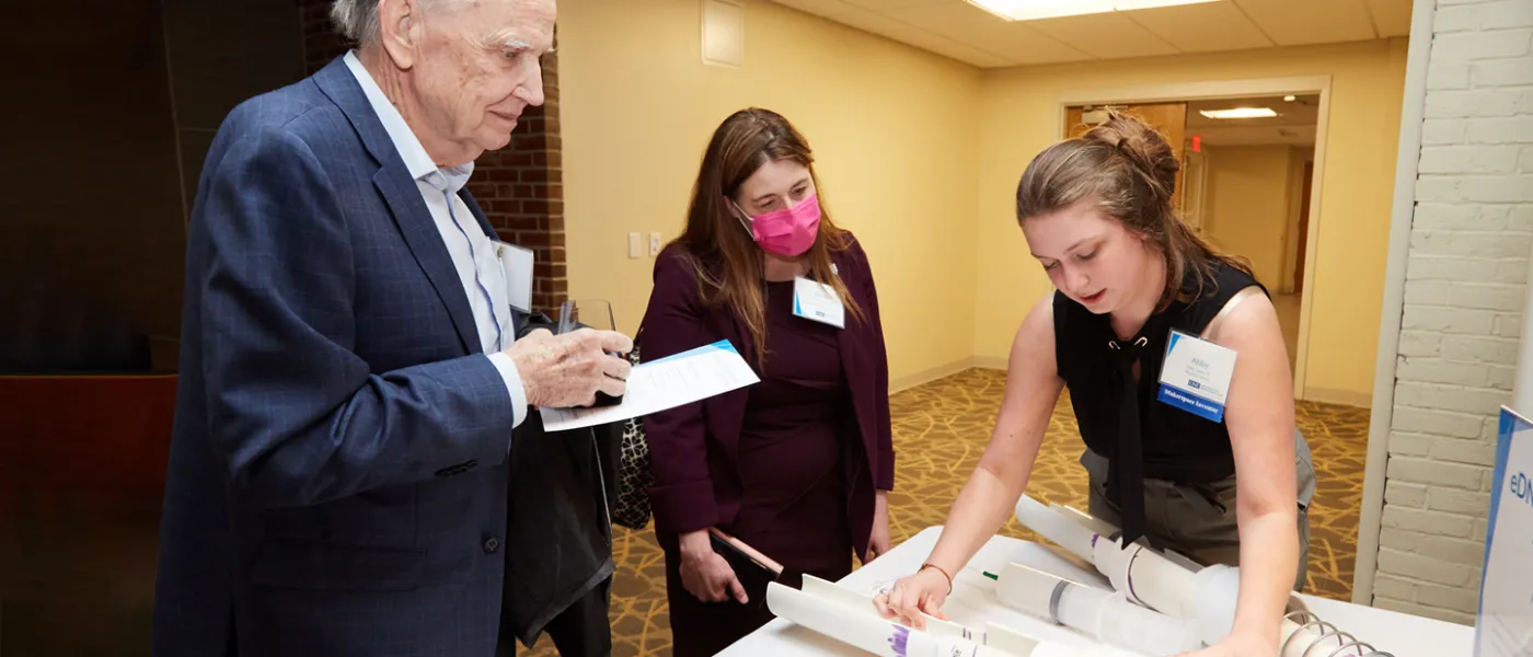 A student shows their project to two judges