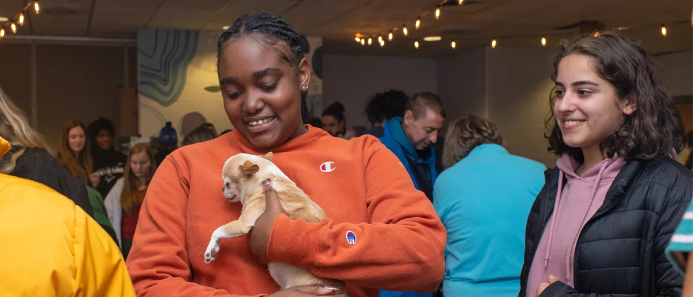 A student holds a puppy at a dog destress event