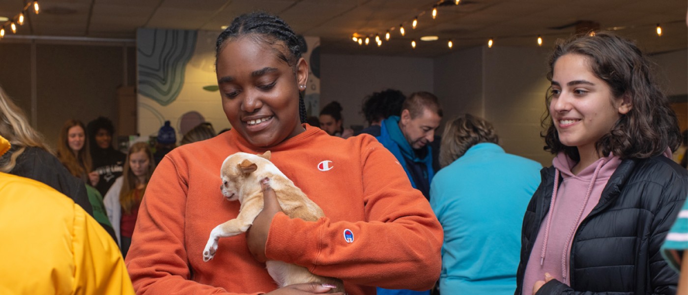 A student holds a puppy at a dog destress event