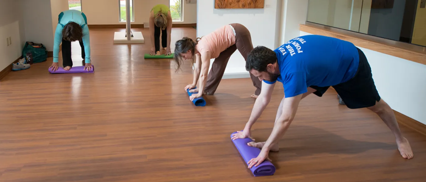 Students perform yoga in the Biddeford Campus art gallery