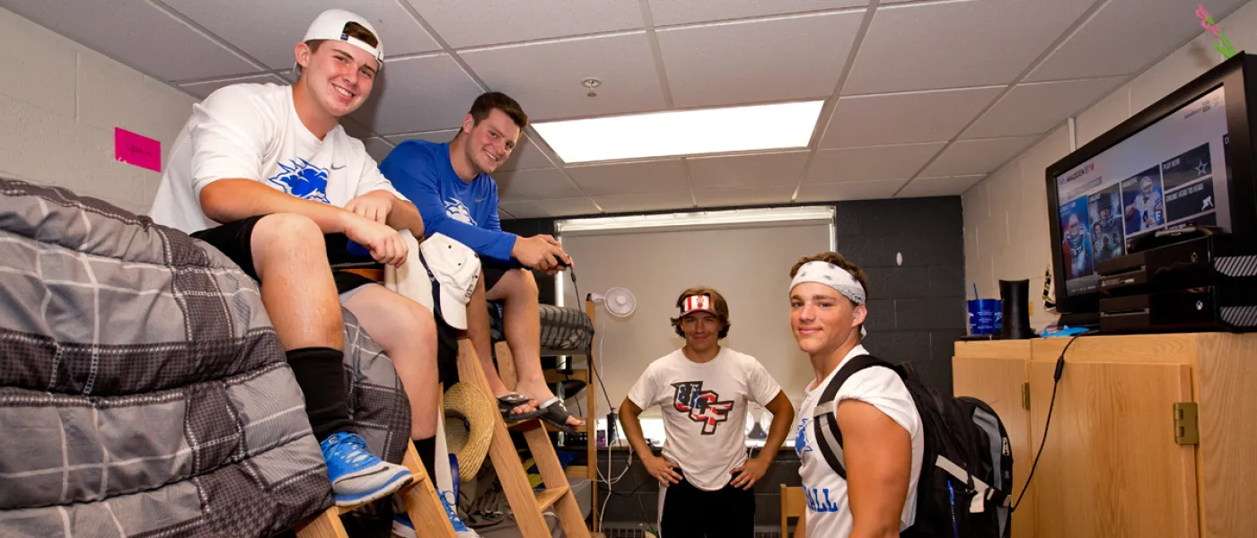 Four students taking a break from moving into their dorm room