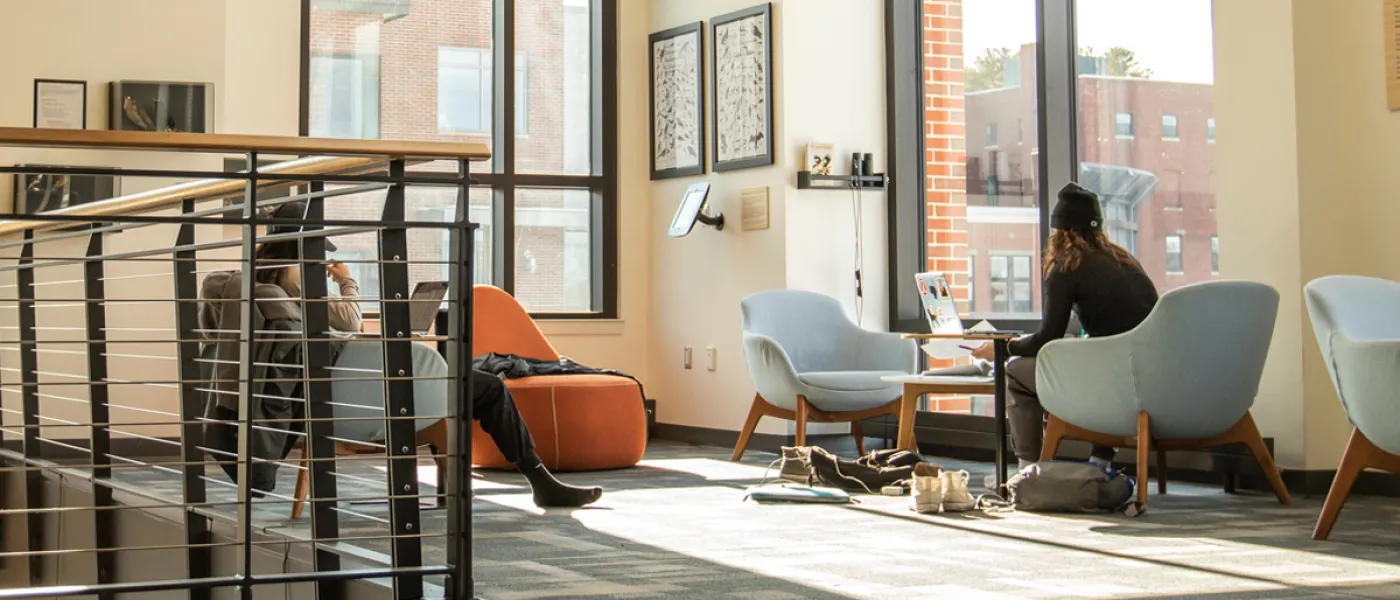 Two students sitting by windows on the second level of the Commons