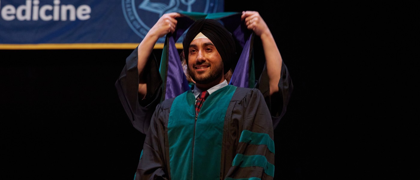 A UNE COM graduate gets hooded at Merrill Auditorium in Portland