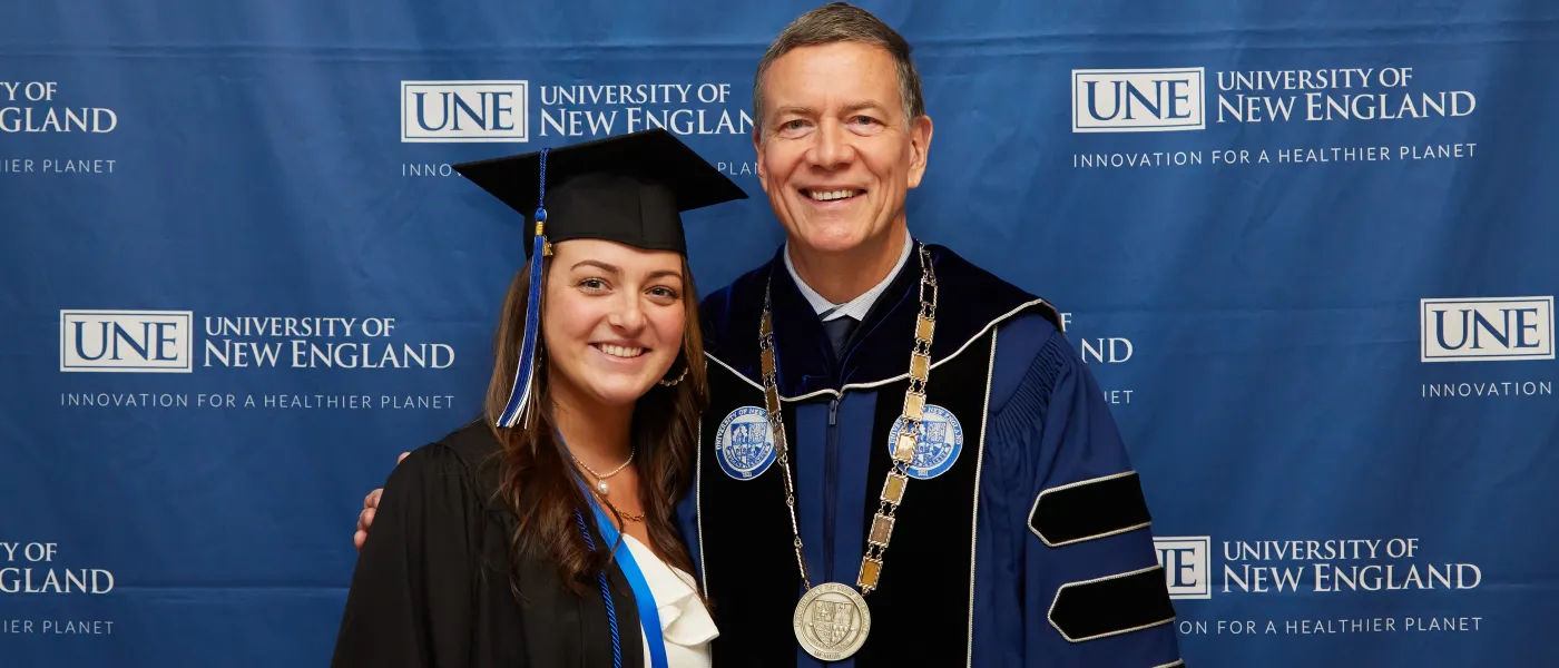 A UNE graduate poses with President James Herbert