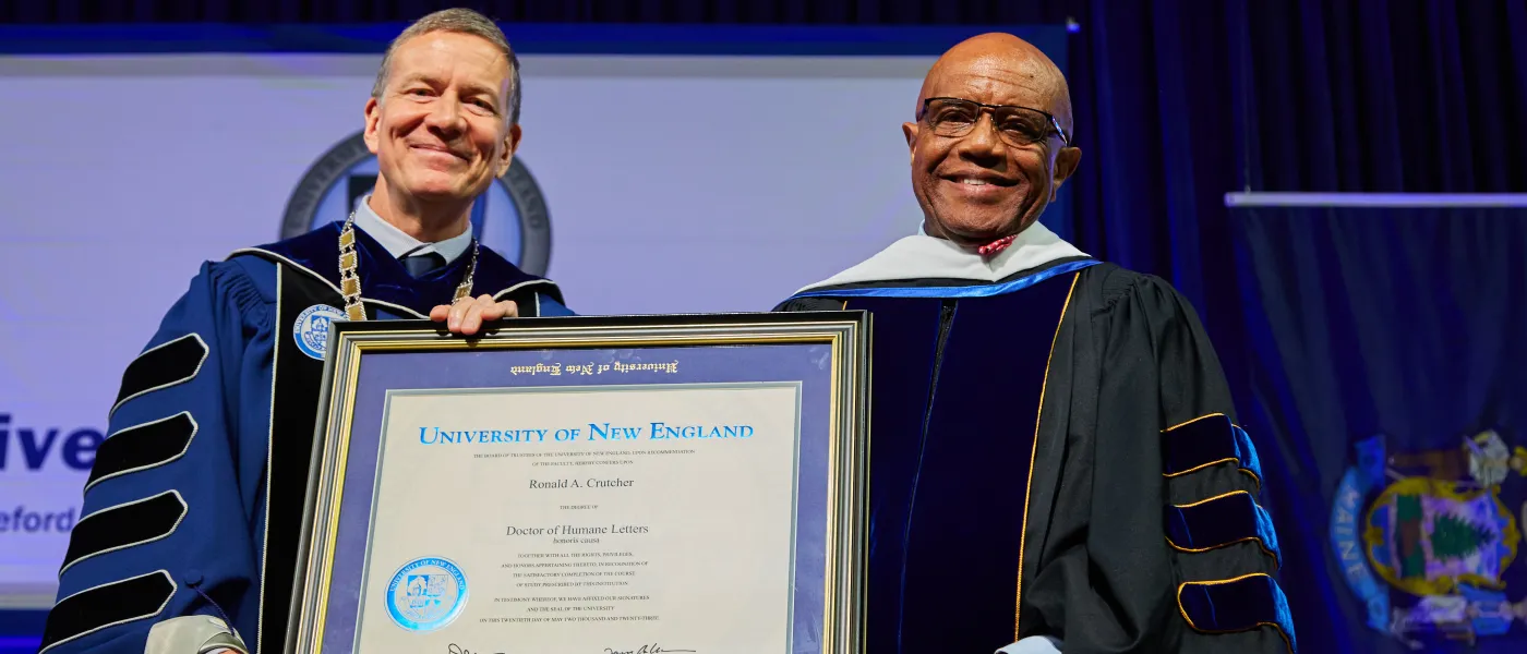 UNE President James Herbert holds an honorary degree awarded to Ronald A. Crutcher