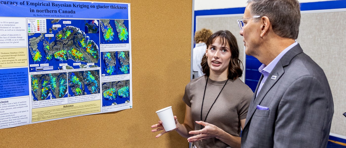 A student talks about their research poster to President Herbert