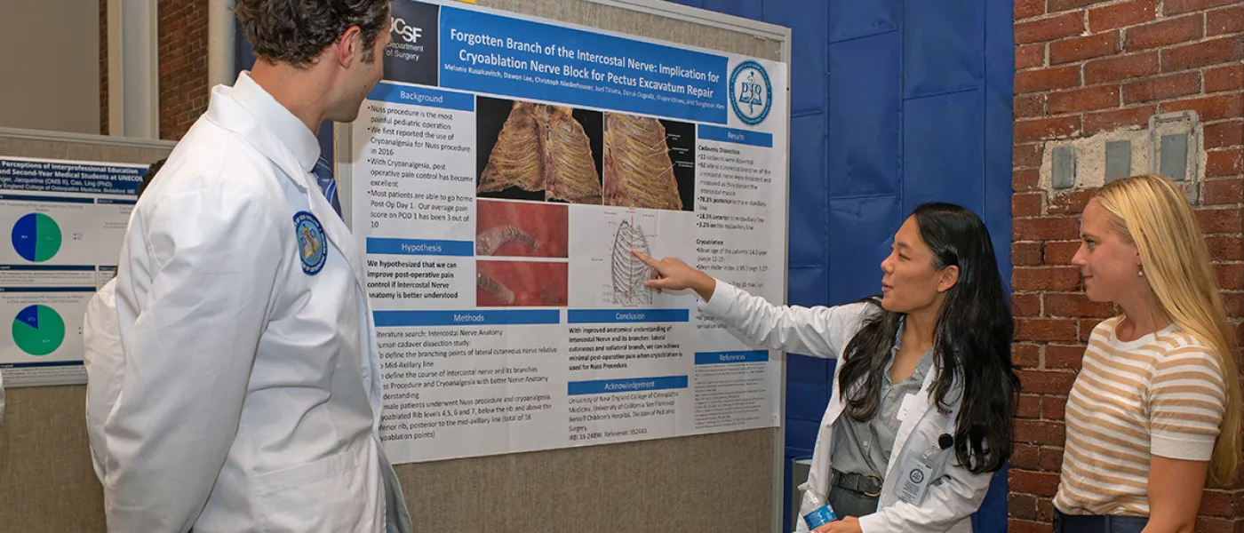 Two C O M students showing their poster presentation