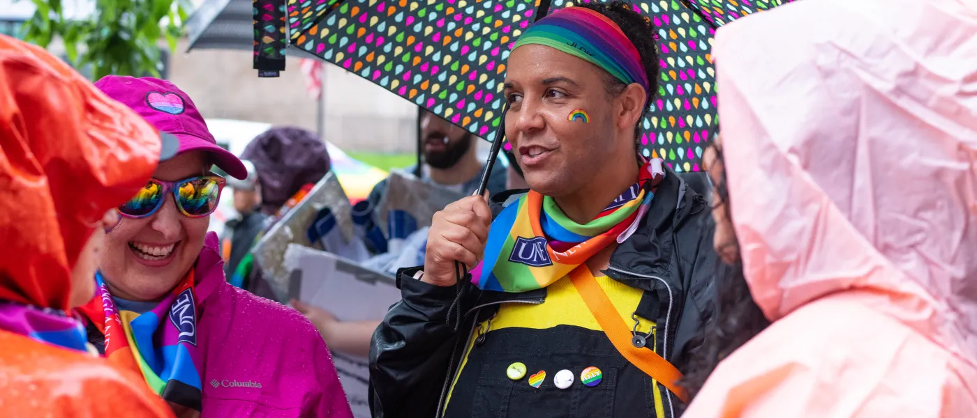 a UNE participant holds a colorful umbrella to fend off the rain