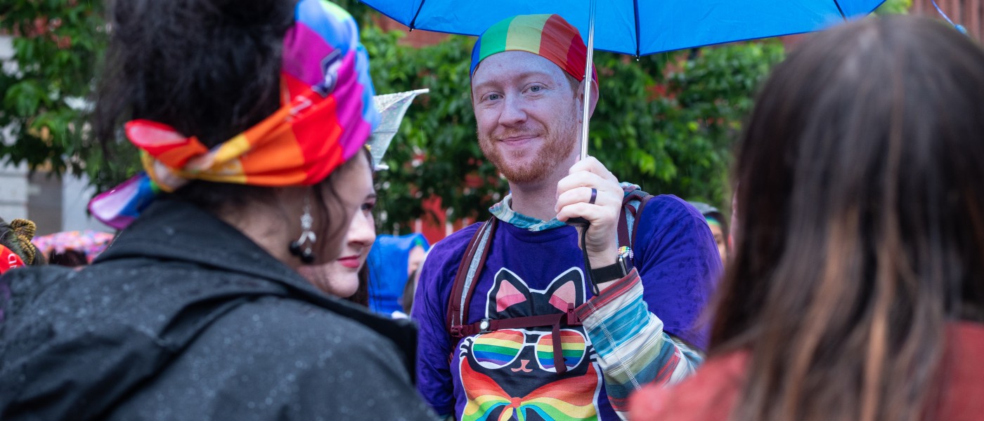 a UNE participant holds a colorful umbrella to fend off the rain