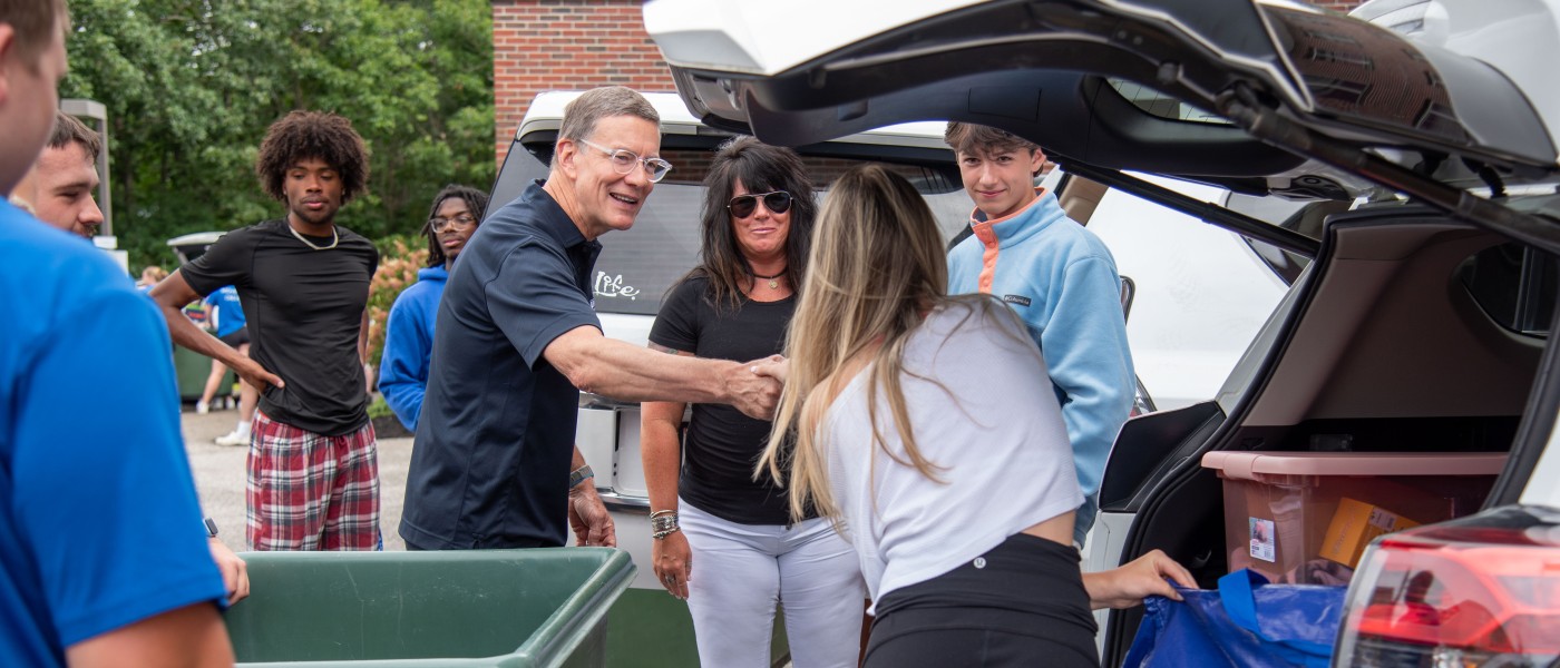UNE President James Herbert helps a family unload their vehicle