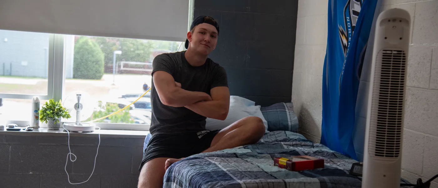 A student poses for a photo in his dorm room