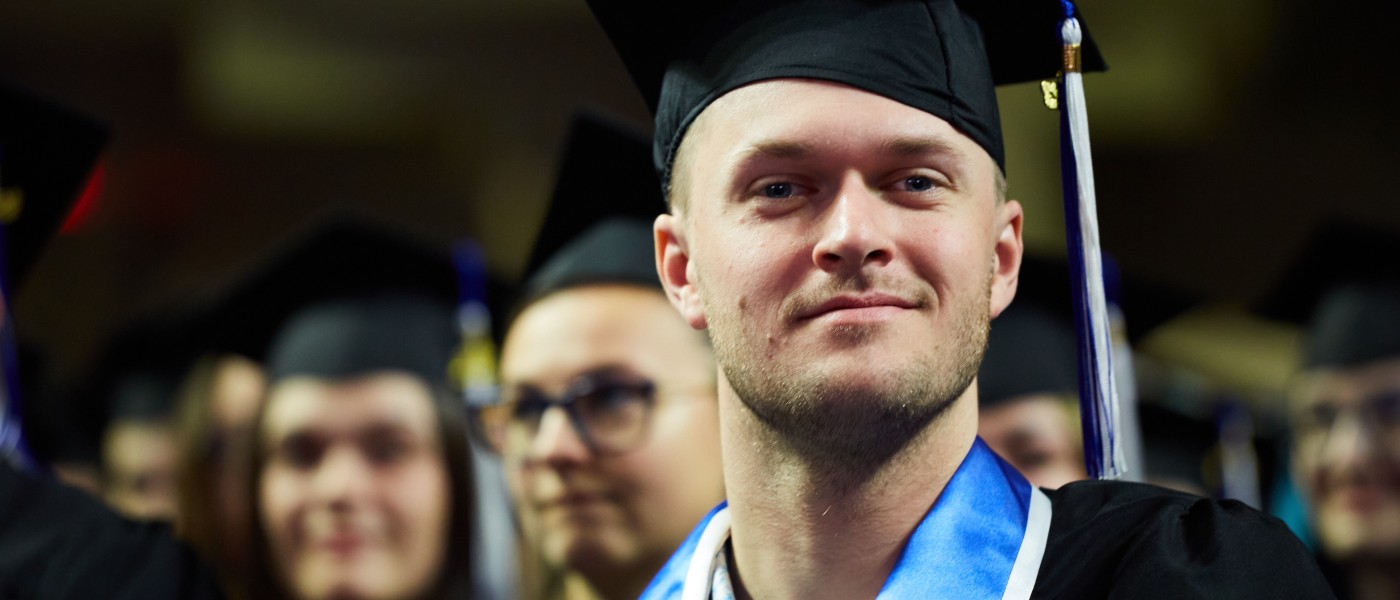 A graduating student sits in the crowd at commencement