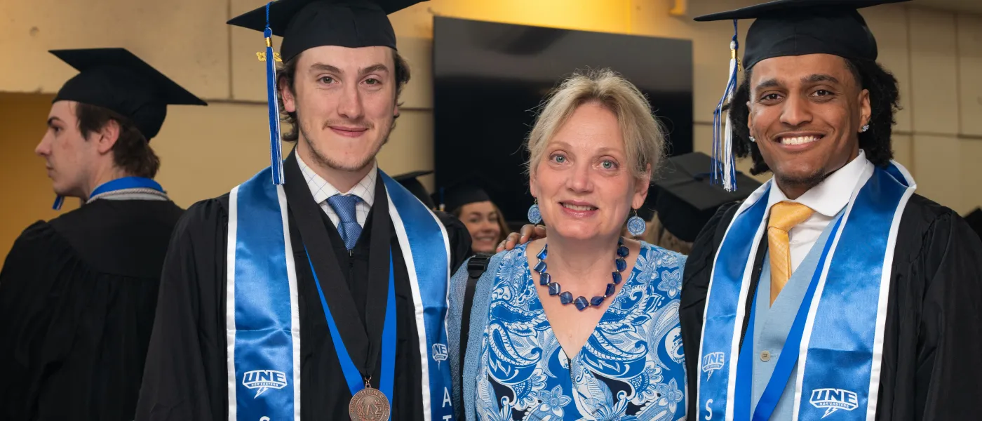 Students pose with a faculty member at U N E's 2023 commencement