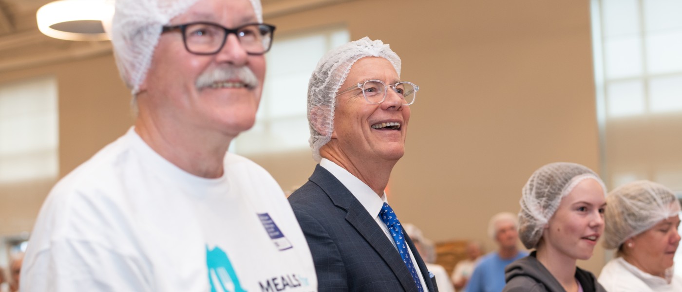 U N E President Herbert and fellow Meals for Maine volunteers wear head nets and latex gloves