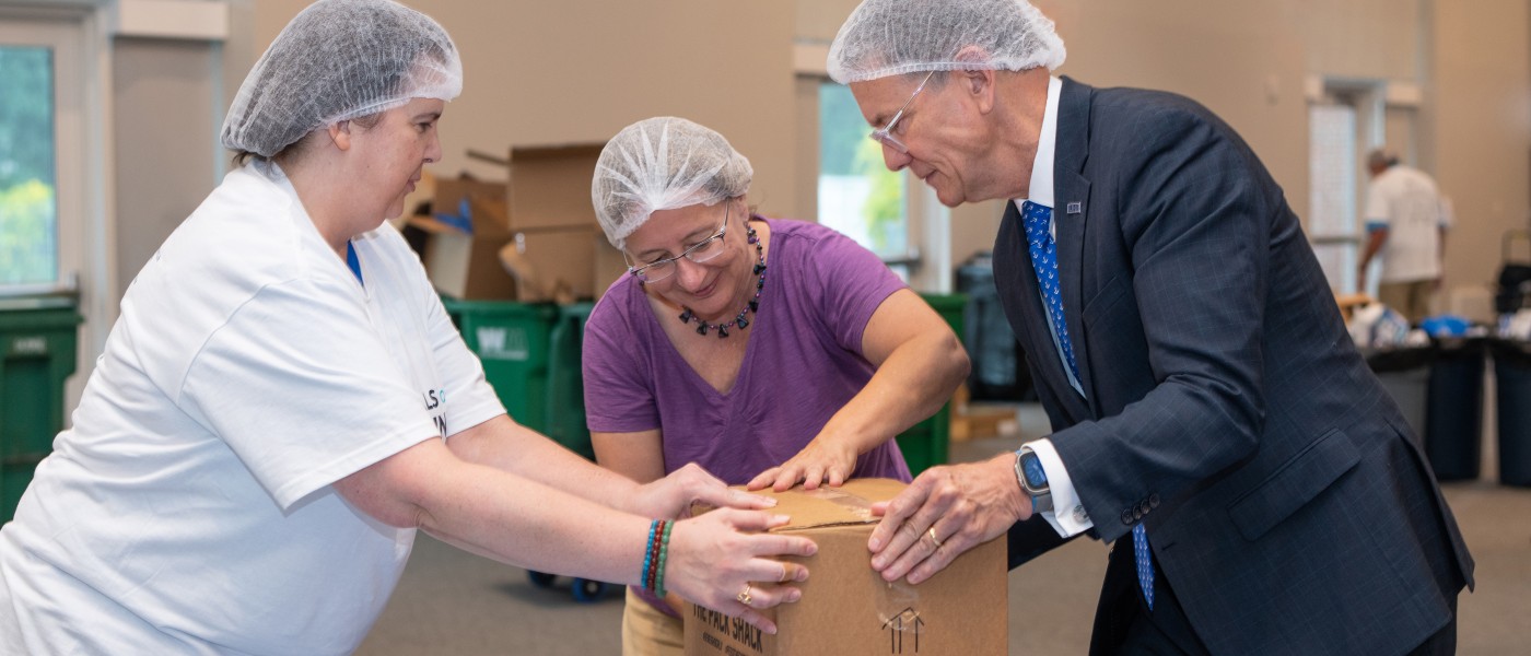 U N E President Herbert and fellow Meals for Maine volunteers packing a box