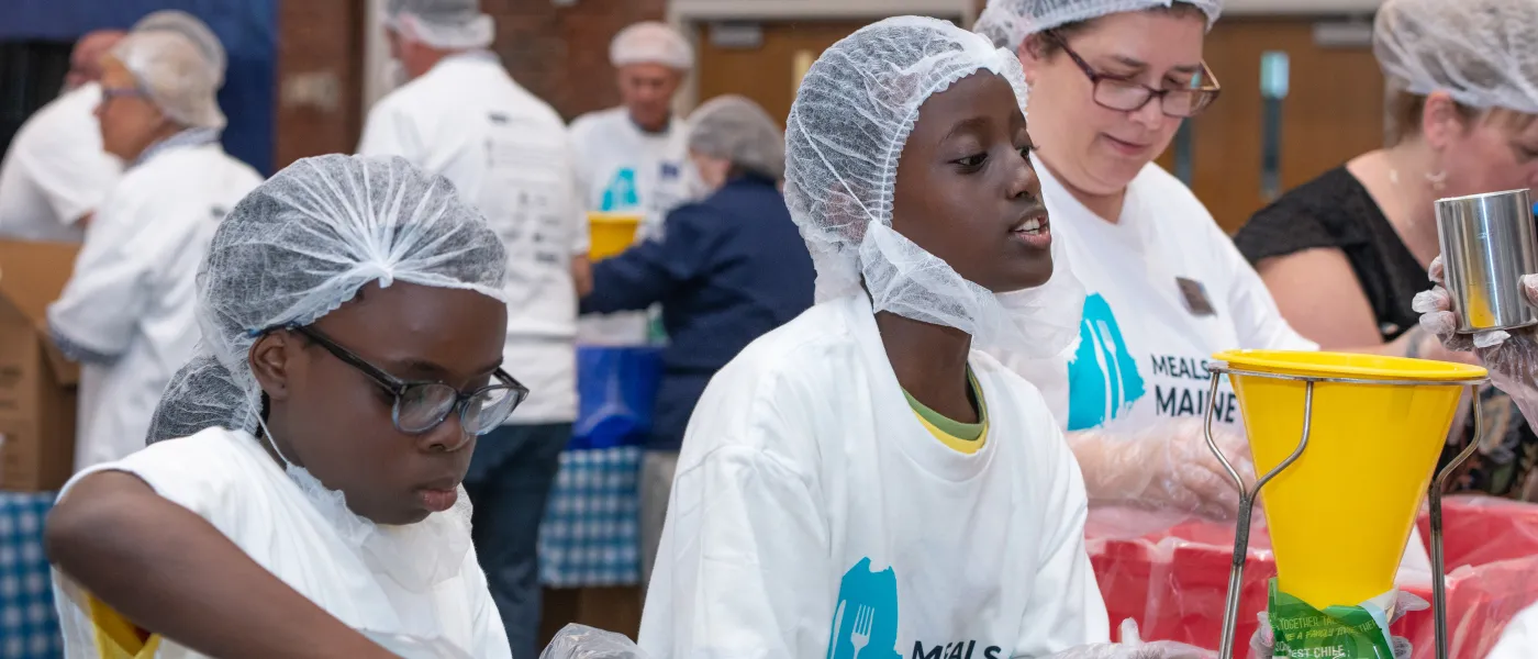 Two children volunteers help pack food for Meals for Maine