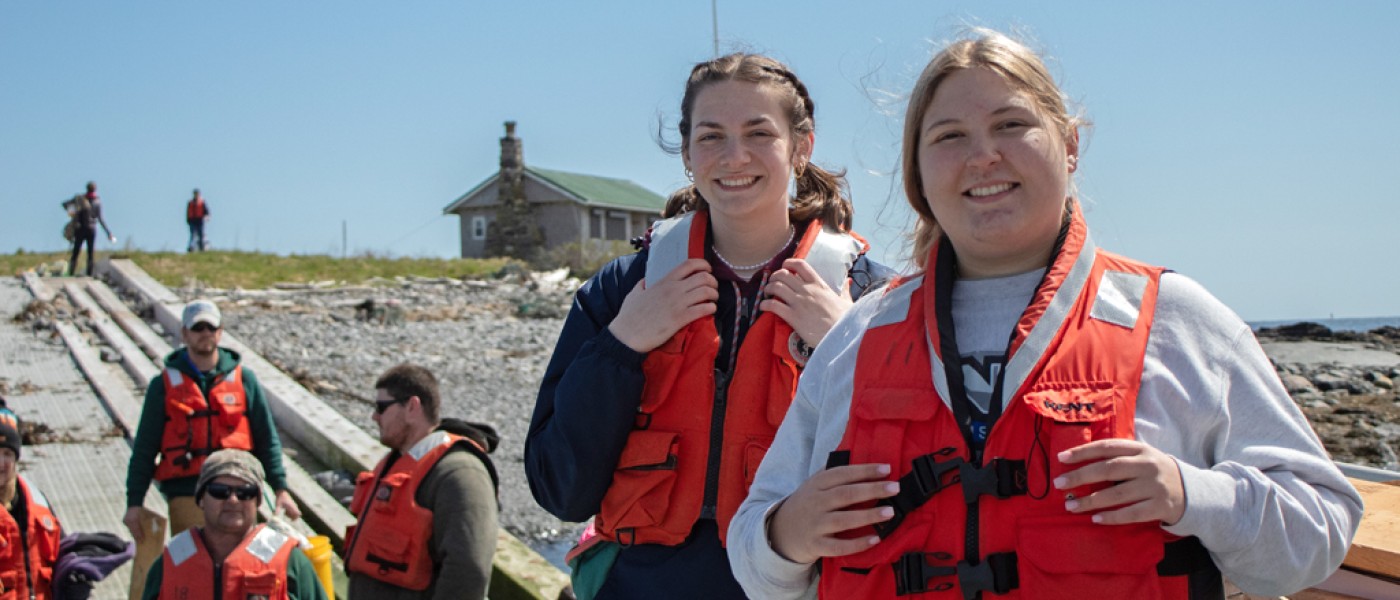 Students in life vests walk up to the lighthouse on Ram Island