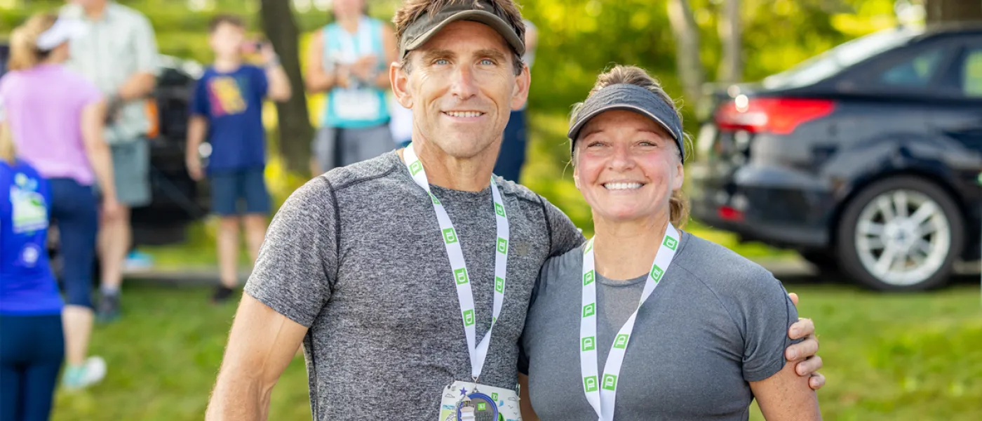Two U N E employees pose together after running the Beach to Beacon 10K Road Race