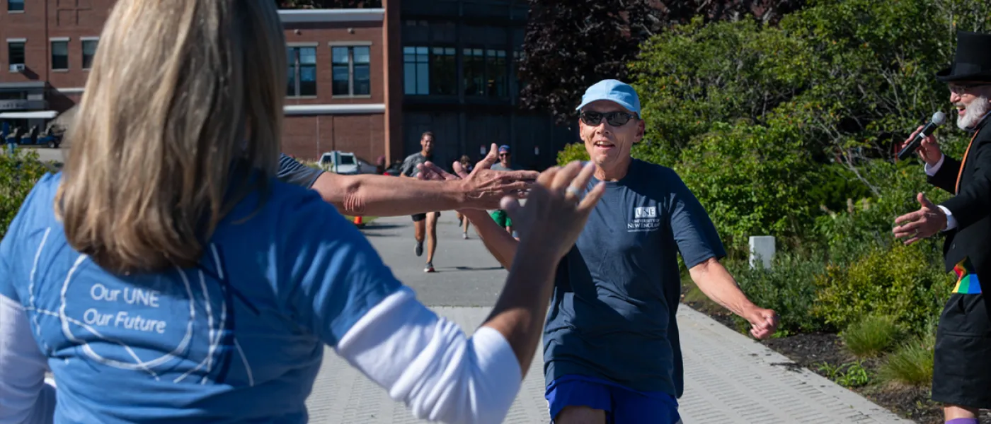U N E employees high-fiving during the annual fall assembly fun run