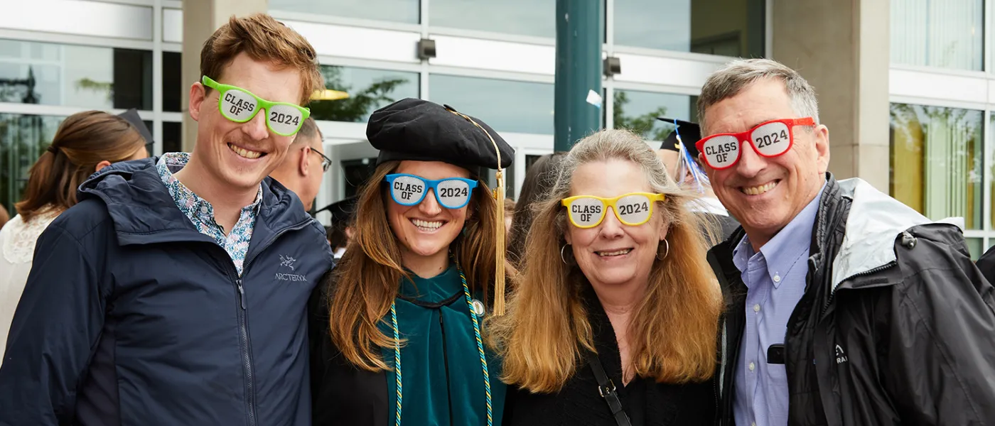 A graduate and her family smile at the camera in sunglasses that lenses read Class of and 2024