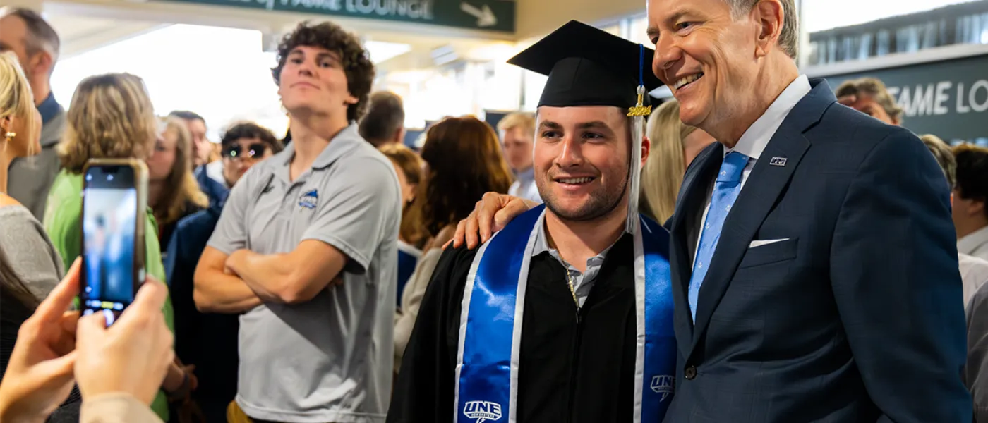U N E President James Herbert pauses to snap a photo with a graduate student after commencement.