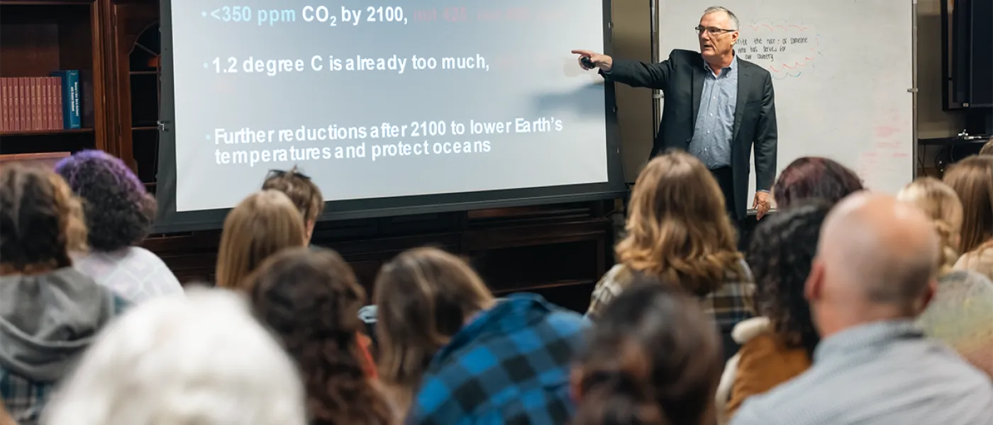 A lecturer reads from their slide on, "Science-based standards to protect children's human rights" a projector to an audience