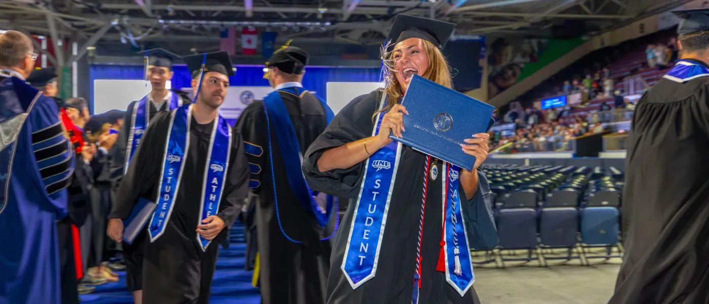 A graduate cheers after receiving her diploma