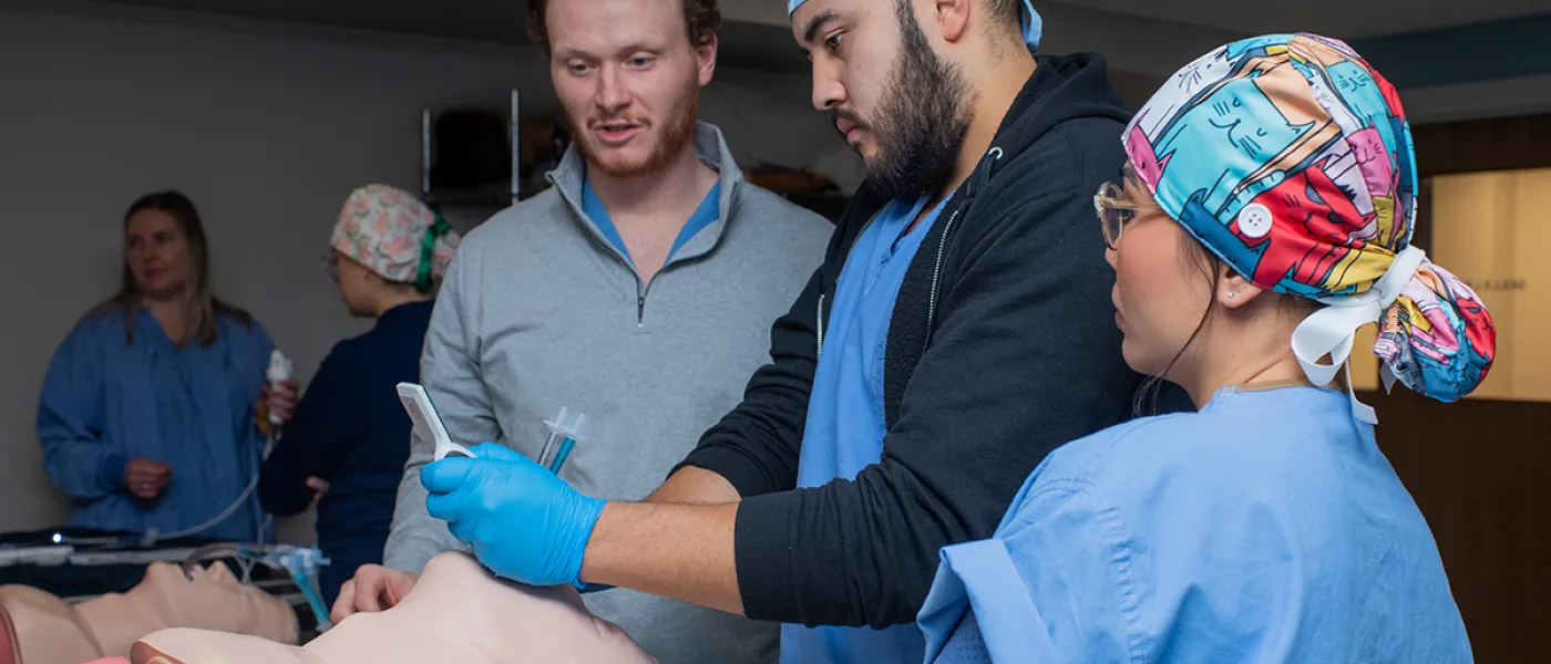 Three nursing anesthesia students practice giving anesthesia to a patient simulator