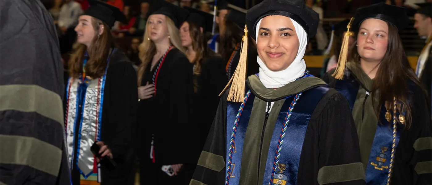 A graduating student smiles from the crowd at commencement