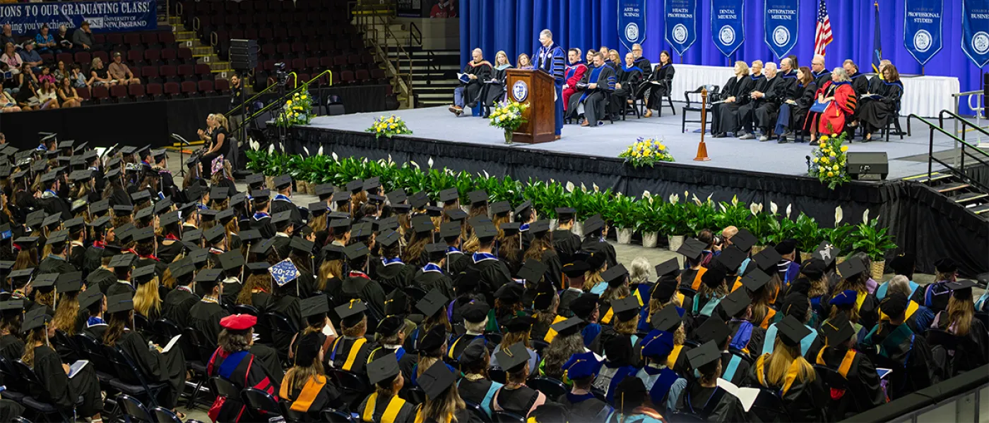 A view of the student crowd and stage featuring President Herbert speaking at the 2025 University Commencement Ceremony