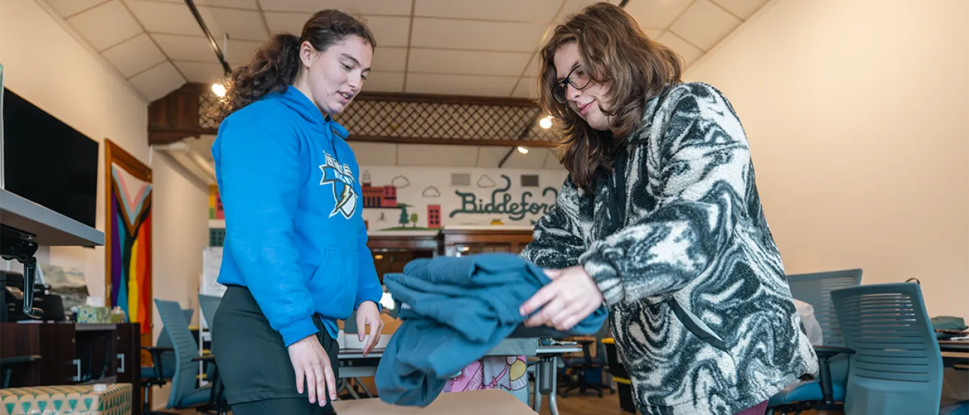 Two U N E students prep a blanket to be donated