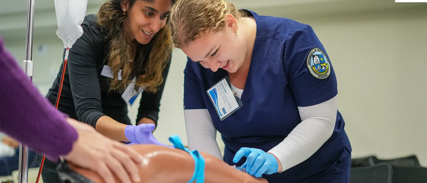 A nursing student practices injecting a needle into a simulated patient arm