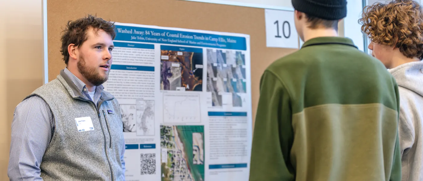A student presents their coastal erosion poster to two individuals