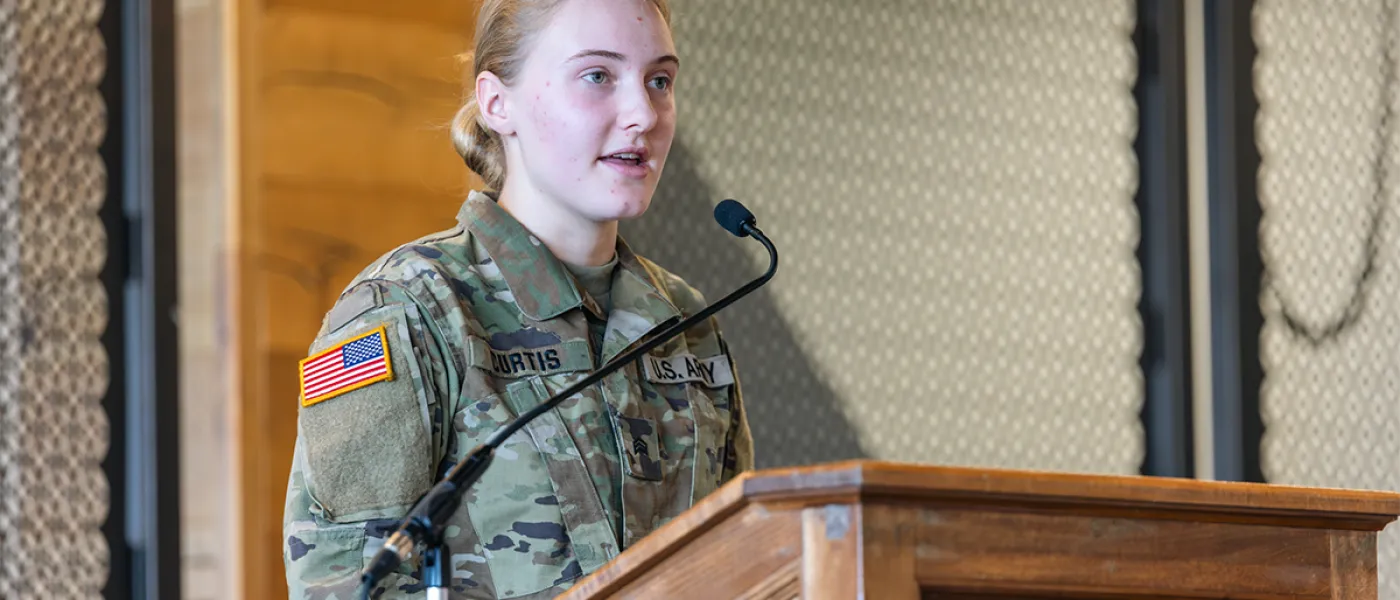 A veteran in an army uniform speaks at a podium