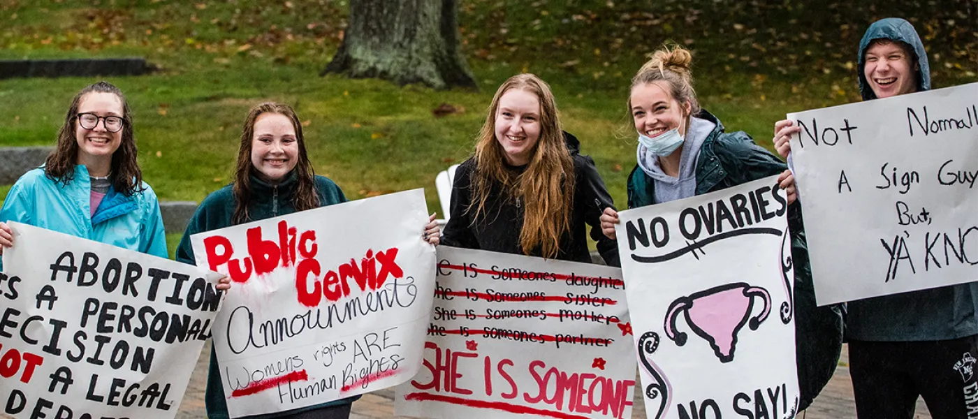 Five students holding up protest signs during a Women's March